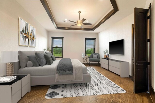 bedroom featuring visible vents, wood finished floors, ceiling fan, and a tray ceiling