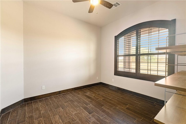 empty room with dark wood-style flooring, visible vents, ceiling fan, and baseboards
