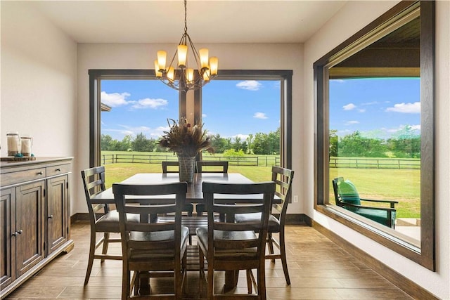 dining room with baseboards, wood finished floors, a notable chandelier, and a healthy amount of sunlight