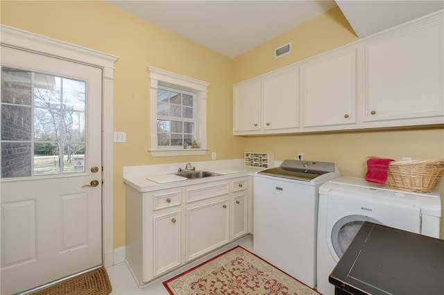 washroom featuring cabinet space, a sink, visible vents, and washer and dryer