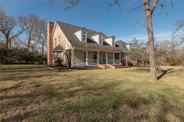 view of front of property with covered porch, roof with shingles, a chimney, and a front yard