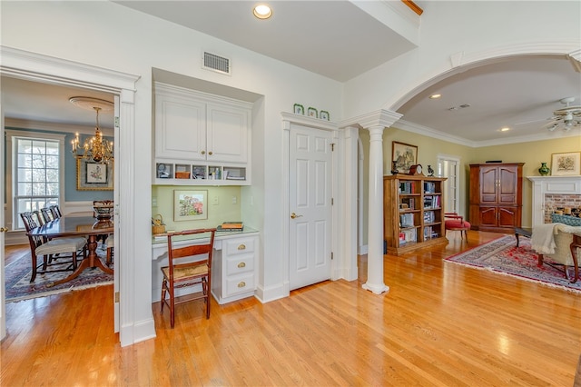 interior space with arched walkways, visible vents, light wood-style floors, decorative columns, and crown molding