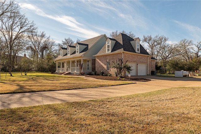 view of side of home with a garage, concrete driveway, covered porch, a yard, and brick siding