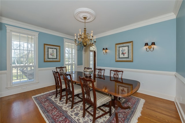 dining area with an inviting chandelier, ornamental molding, and wood finished floors