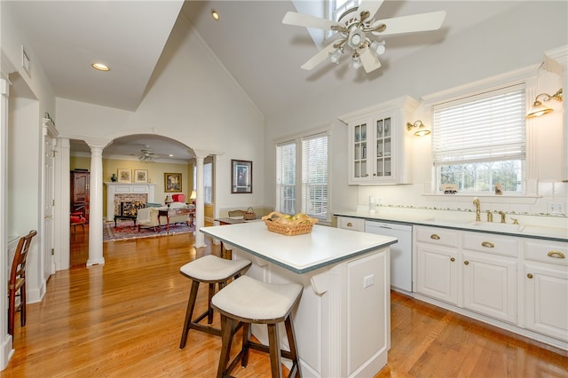 kitchen with a brick fireplace, a ceiling fan, dishwasher, ornate columns, and a sink