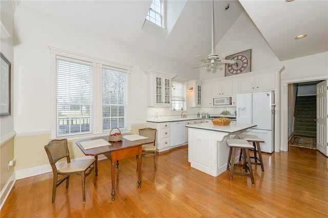 kitchen with white appliances, white cabinets, light wood-style floors, and a center island