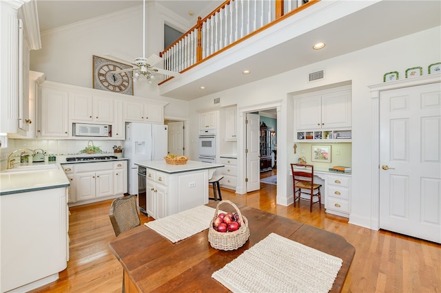 kitchen with light wood-style flooring, white appliances, a sink, visible vents, and white cabinetry