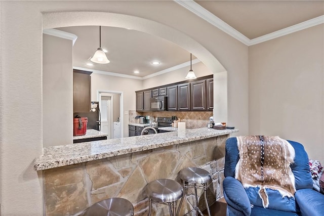 kitchen featuring a kitchen breakfast bar, black appliances, light stone counters, dark brown cabinets, and decorative light fixtures