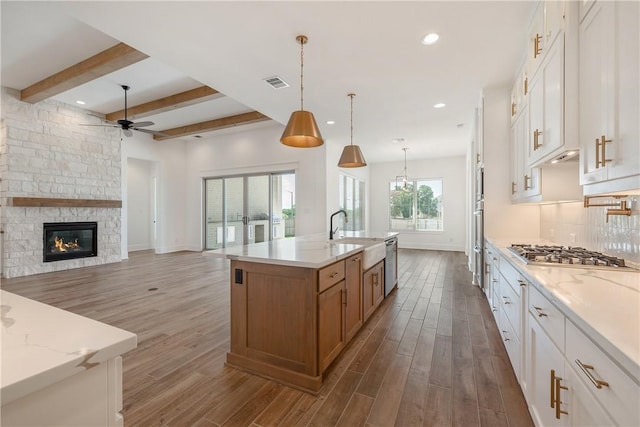 kitchen with white cabinetry, appliances with stainless steel finishes, sink, and light stone counters