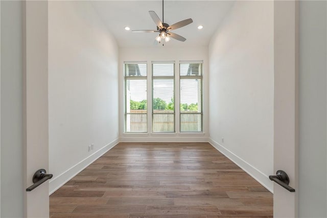 empty room with lofted ceiling, wood-type flooring, and ceiling fan