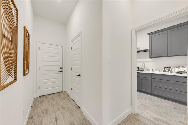 hall with light hardwood / wood-style floors and sink