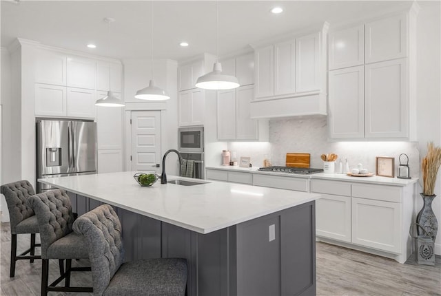 kitchen with white cabinetry, sink, decorative light fixtures, a center island with sink, and appliances with stainless steel finishes