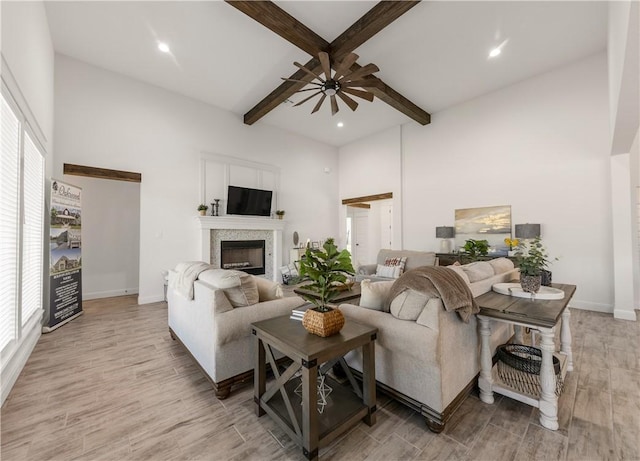 living room with beam ceiling, ceiling fan, light hardwood / wood-style flooring, and a healthy amount of sunlight