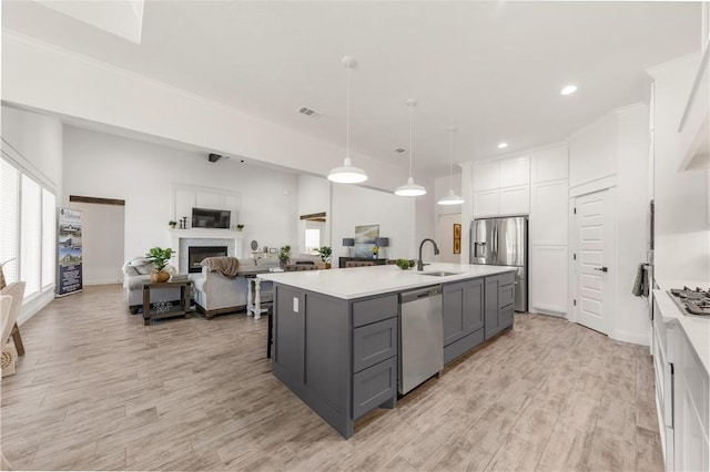 kitchen featuring gray cabinetry, white cabinetry, sink, stainless steel appliances, and a center island with sink