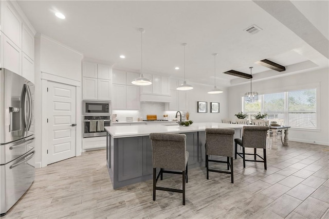 kitchen with white cabinets, a spacious island, light wood-type flooring, decorative light fixtures, and stainless steel appliances