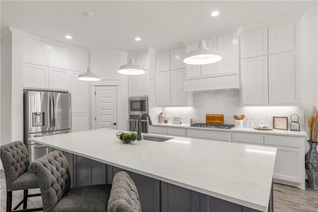 kitchen with decorative light fixtures, sink, stainless steel appliances, and a large island with sink