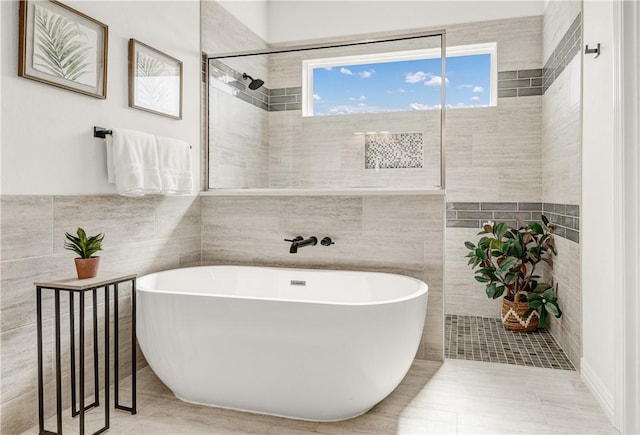 bathroom with tile patterned flooring, tile walls, and plus walk in shower