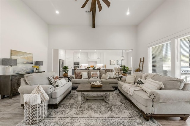 living room featuring a high ceiling, light hardwood / wood-style floors, and ceiling fan