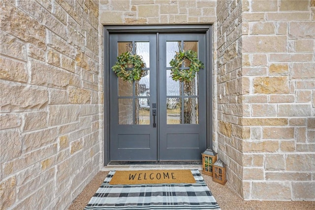 doorway to property featuring stone siding, french doors, and brick siding