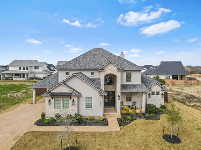 french country style house featuring stone siding, a front lawn, a chimney, and a residential view