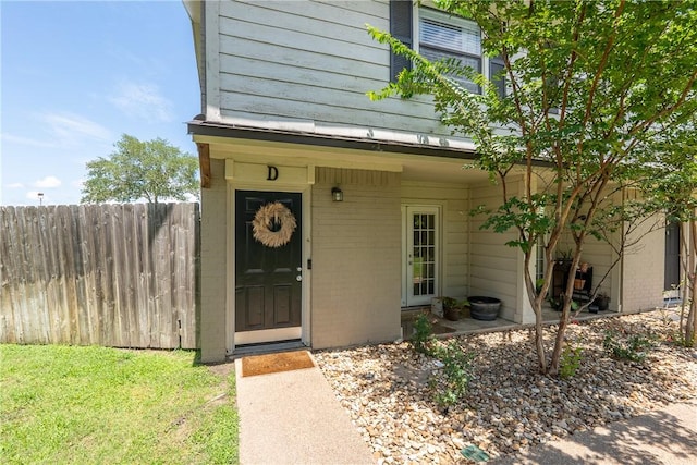 property entrance with brick siding and fence