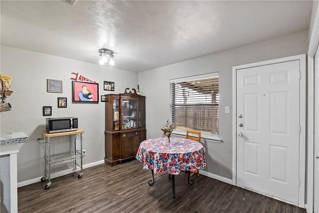 dining area with a textured ceiling, wood finished floors, and baseboards