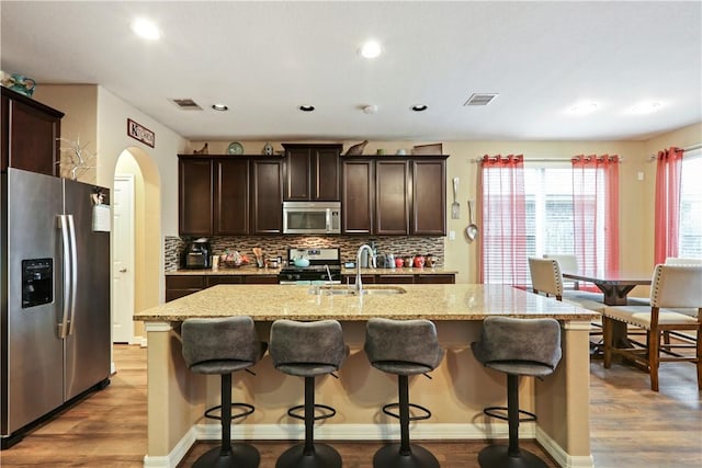 13423 Ashley Acres Ln, Cypress, TX 77429 - kitchen featuring stainless steel appliances, wood finished floors, a sink, dark brown cabinetry, and backsplash