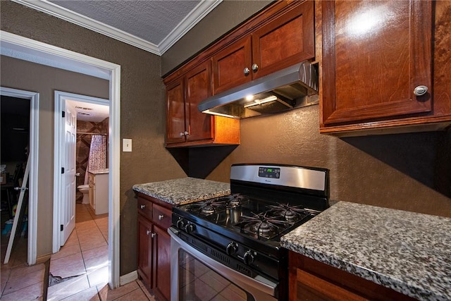 kitchen featuring a textured ceiling, a textured wall, stainless steel gas range oven, under cabinet range hood, and ornamental molding