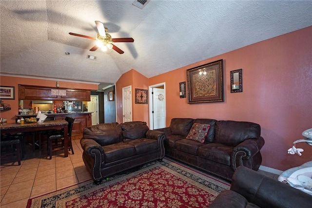 living area featuring visible vents, vaulted ceiling, a textured ceiling, and light tile patterned floors