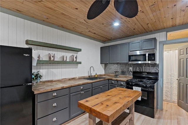 kitchen featuring sink, light hardwood / wood-style floors, wooden ceiling, black appliances, and butcher block counters