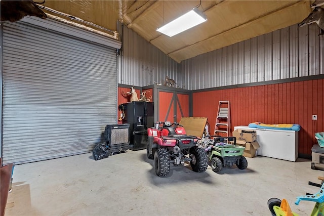 garage with wood walls and black fridge with ice dispenser