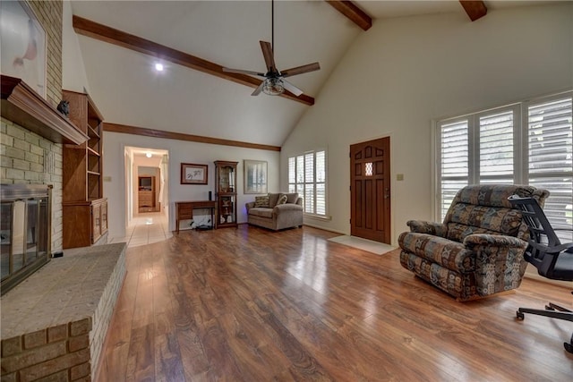 living room featuring hardwood / wood-style floors, a brick fireplace, high vaulted ceiling, beam ceiling, and ceiling fan