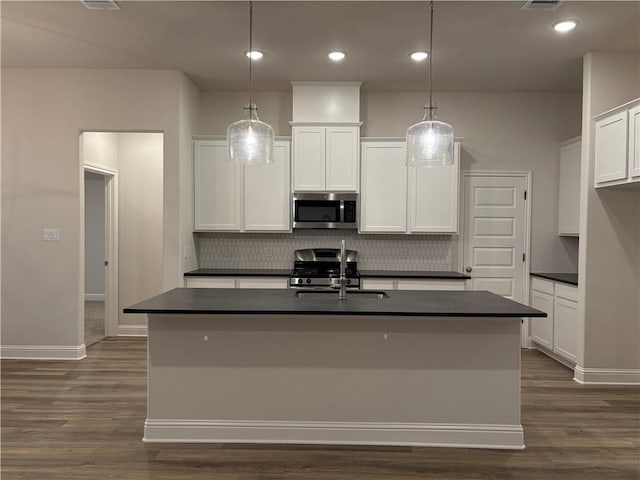 kitchen with white cabinetry, pendant lighting, stainless steel appliances, and a center island with sink