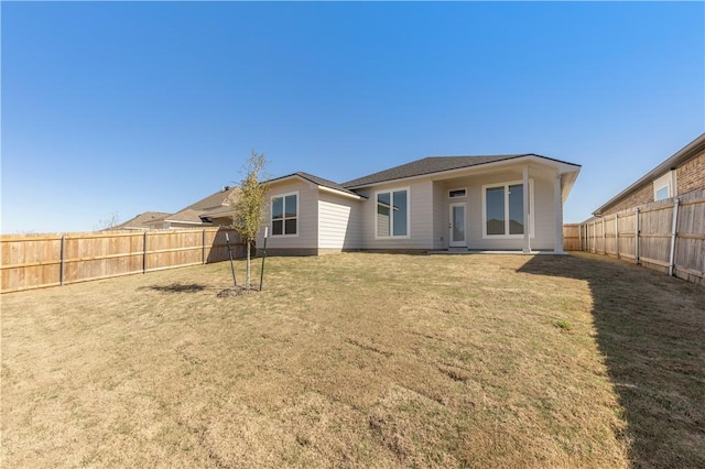 rear view of property featuring a yard and a fenced backyard