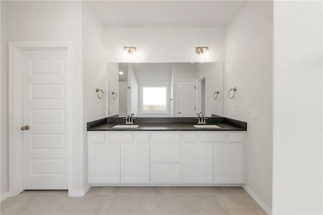 bathroom featuring double vanity, baseboards, and a sink