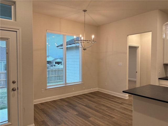 unfurnished dining area featuring a wealth of natural light, dark hardwood / wood-style flooring, and a chandelier