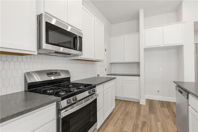 kitchen featuring light wood-style floors, dark countertops, appliances with stainless steel finishes, and white cabinets