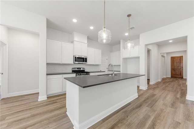 kitchen with visible vents, a sink, appliances with stainless steel finishes, dark countertops, and tasteful backsplash