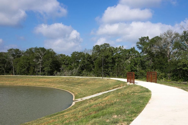 view of community featuring a wooded view, a lawn, and a water view