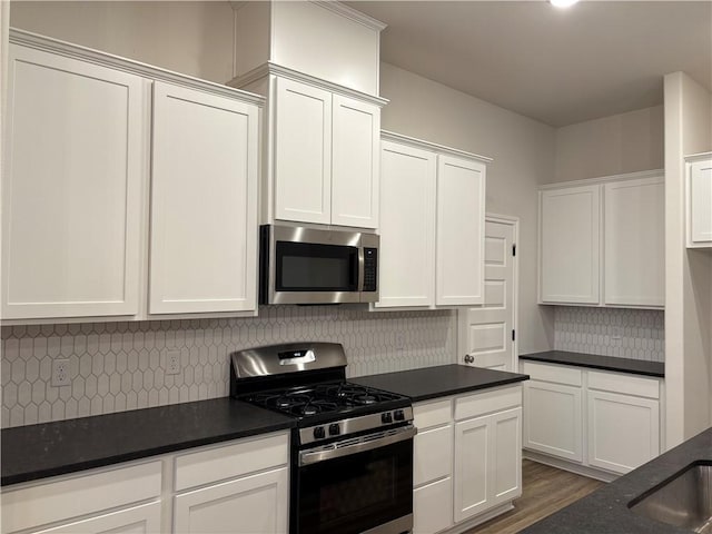 kitchen featuring stainless steel appliances, white cabinetry, tasteful backsplash, and dark hardwood / wood-style floors