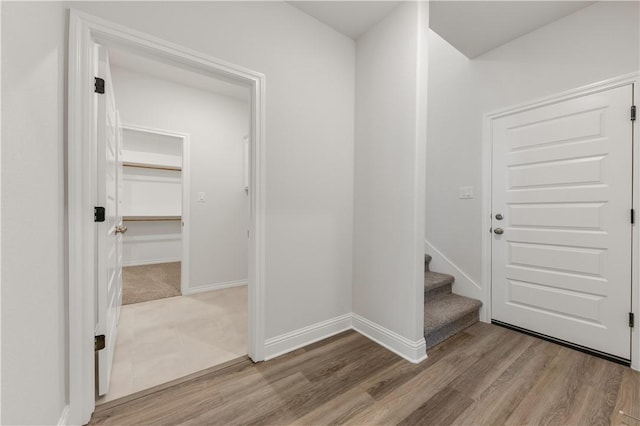 foyer featuring light wood finished floors, stairway, and baseboards