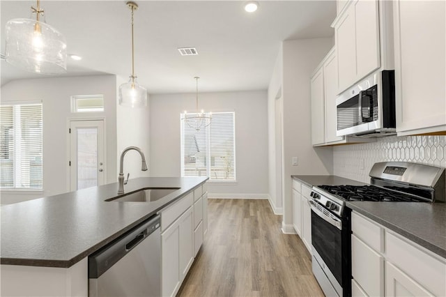 kitchen featuring dark countertops, backsplash, appliances with stainless steel finishes, and a sink