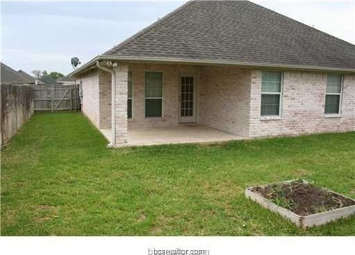 rear view of property with a fenced backyard, a lawn, a garden, a patio, and a shingled roof