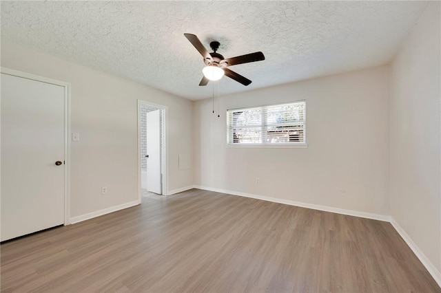 empty room featuring a textured ceiling, light hardwood / wood-style floors, and ceiling fan