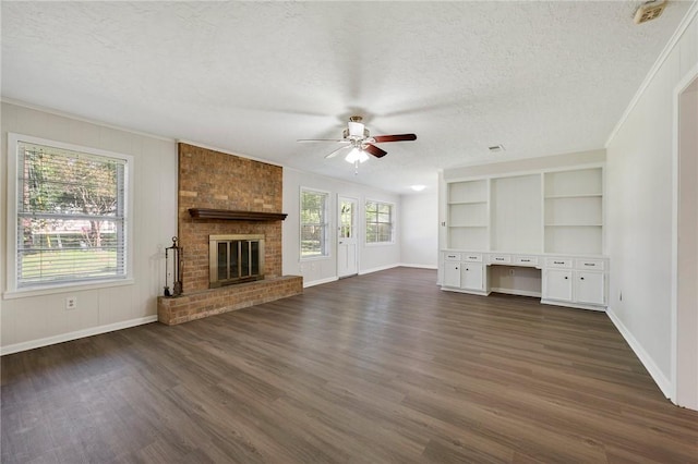 unfurnished living room with ceiling fan, dark hardwood / wood-style floors, crown molding, and a fireplace