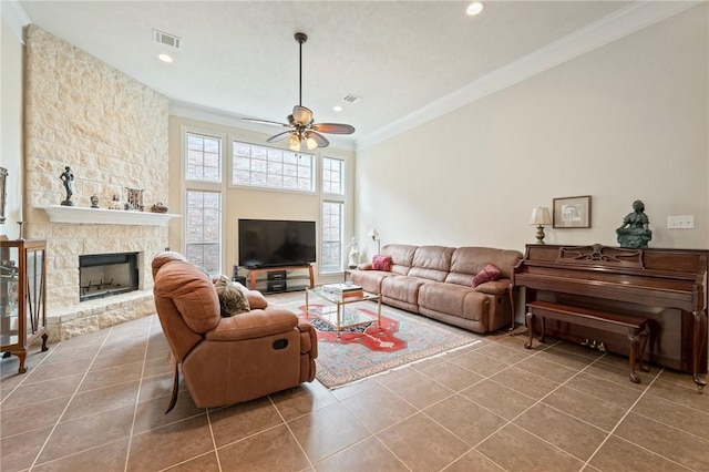 living room featuring a fireplace, ceiling fan, crown molding, and tile patterned flooring
