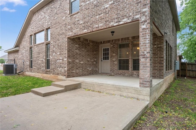 back of house featuring fence, central AC unit, a patio area, and brick siding
