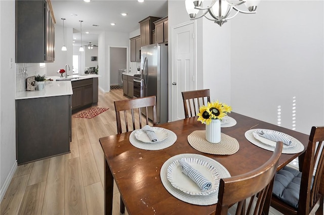 dining area featuring light hardwood / wood-style flooring, sink, and a notable chandelier