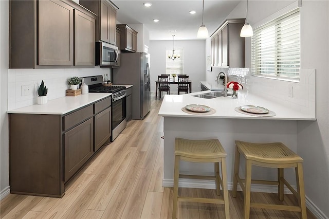 kitchen featuring sink, a kitchen breakfast bar, stainless steel appliances, and pendant lighting