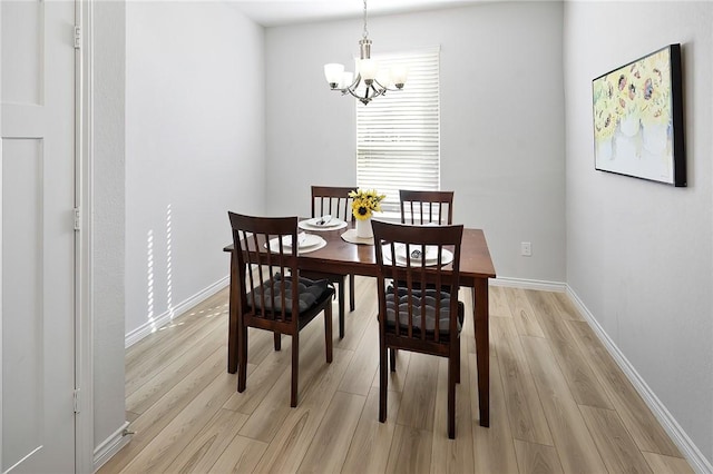 dining space with light hardwood / wood-style floors and a chandelier